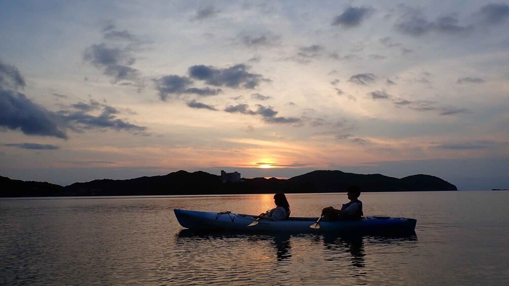 Two people in a kayak on a calm body of water with a sunset in the background. 3