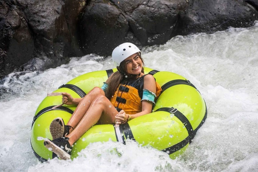 A person in a green inflatable raft navigating a river with rapids. 2
