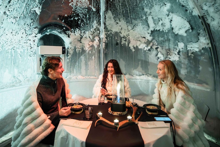 Three people sitting at a table inside a tent with a frosty interior. 4