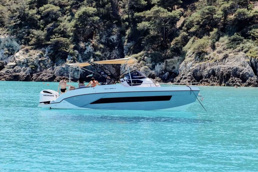 A white boat with a Honda outboard motor on clear turquoise water. 2