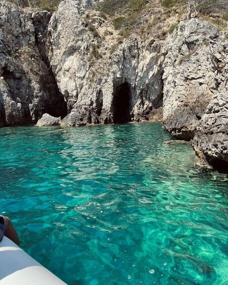 A clear turquoise sea with rocky cliffs and a cave entrance. 3