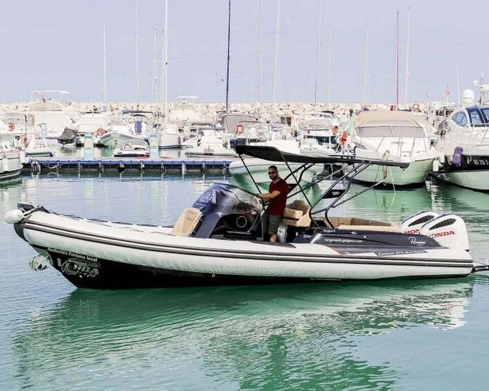 A small motorboat with a person on board, docked in a marina with multiple boats. 5