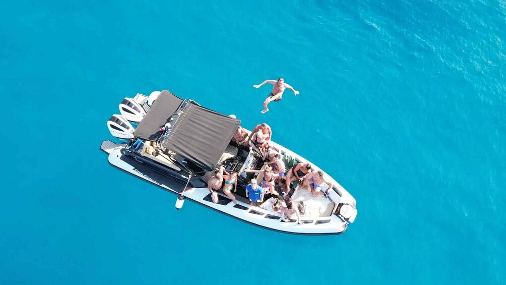 A boat with people on board and one person swimming in the water. 1