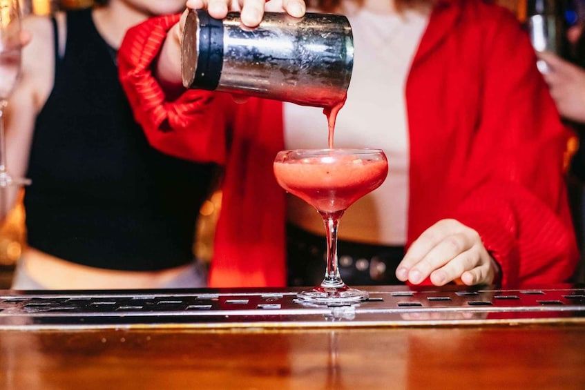 A bartender pouring a drink into a martini glass. 3