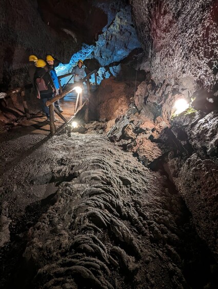 A cave with rocky formations and explorers using headlamps. 2