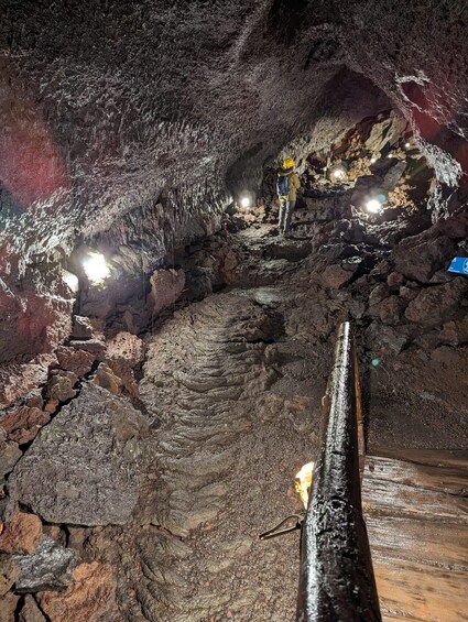 A cave with rocky formations and a person wearing a helmet and carrying a backpack. 5