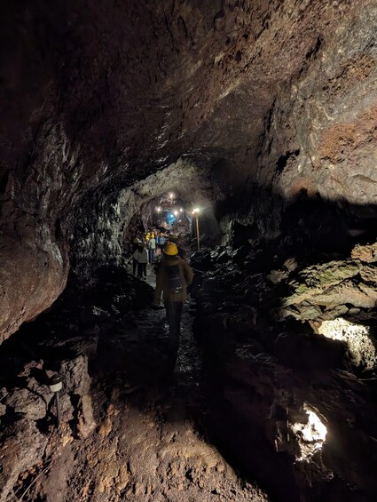 A group of people walking through a dimly lit cave with artificial lighting. 4