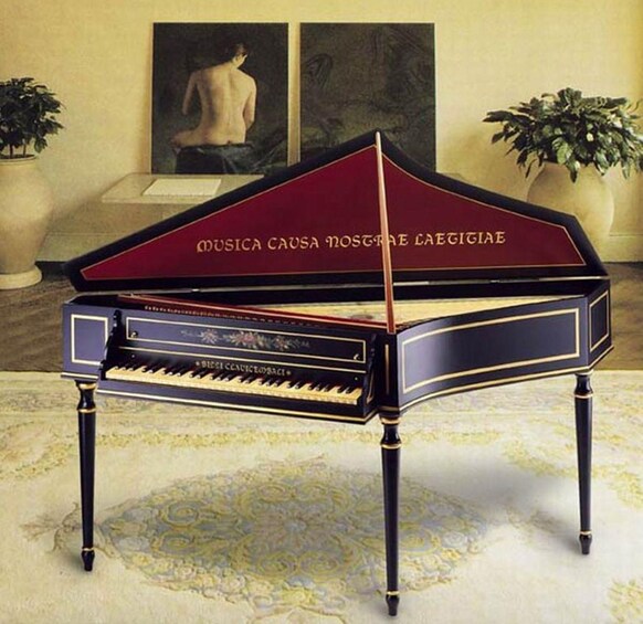 A grand piano with a maroon finish and gold trim, placed on a patterned carpet in a room with classical decor. 3