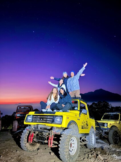 A group of people on a yellow off-road vehicle with a mountainous backdrop. 1