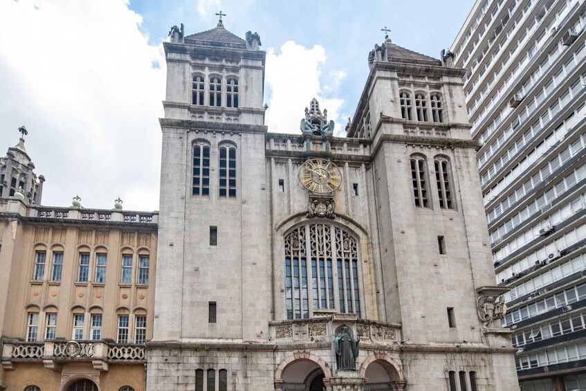 A historic building with a clock tower, arched windows, and statues. 5