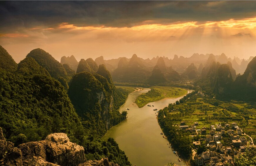 A river winding through a mountainous landscape with a small settlement along its banks. 2