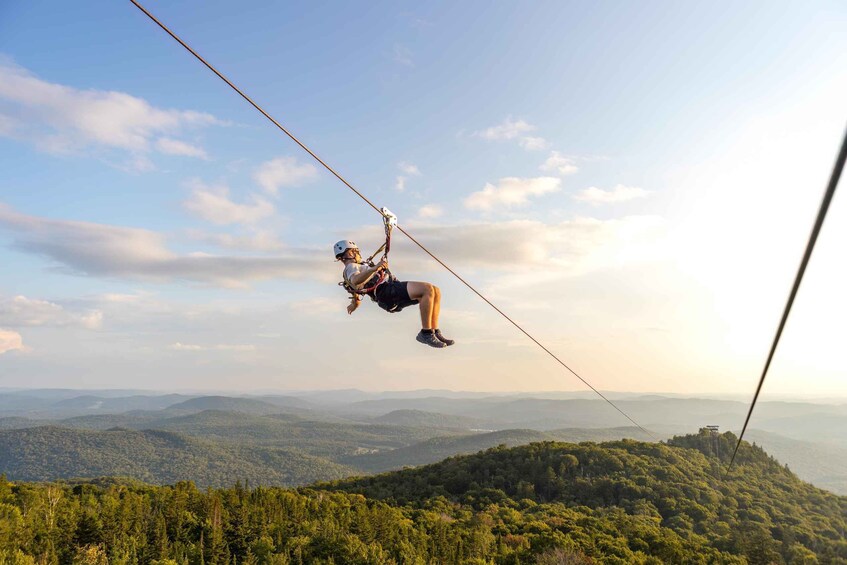 A person bungee jumping with a harness, suspended by a cable against a backdrop of a mountainous landscape. 2