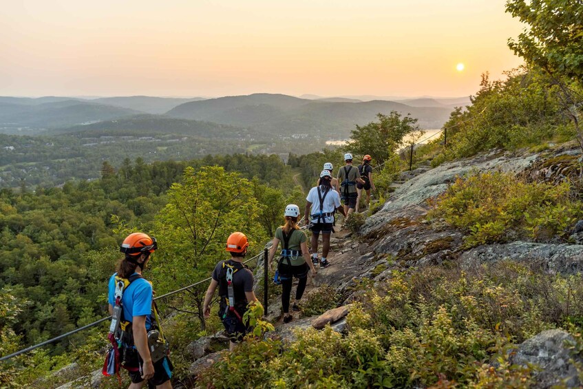 A group of people hiking on a rocky trail with a scenic view of a valley and mountains in the background. 4