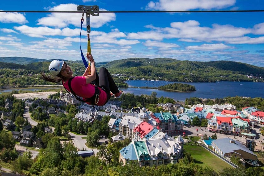 A person ziplining over a town with colorful buildings and a lake in the background. 1