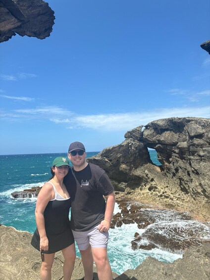Two people standing on a rocky coastline with the ocean in the background. 5
