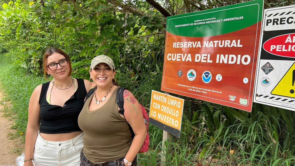 Two people standing in front of a sign for Reserva Natural Cueva del Indio. 3