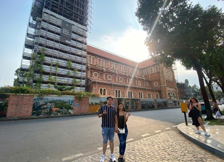 A historic building with a clock tower, a modern building under construction with scaffolding, and pedestrians on a city street. 4