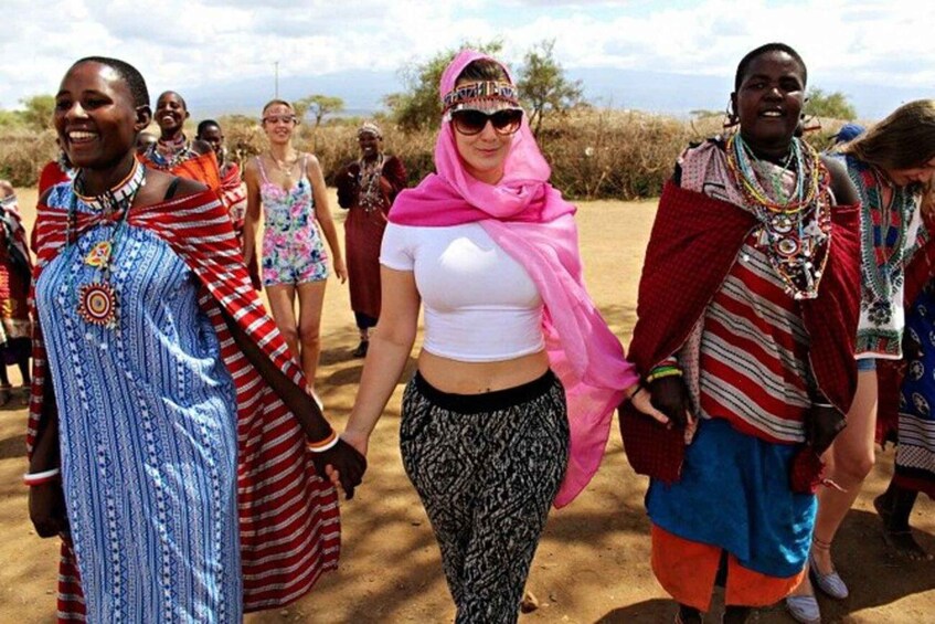 A group of people in traditional and modern attire walking in a dry, open landscape. 2