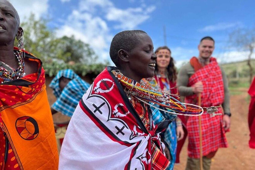A group of people in traditional attire with intricate beadwork and patterns, standing outdoors. 1