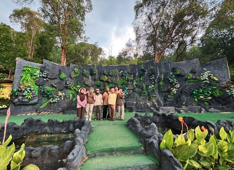 A group of people posing in front of a rock wall with greenery. 5