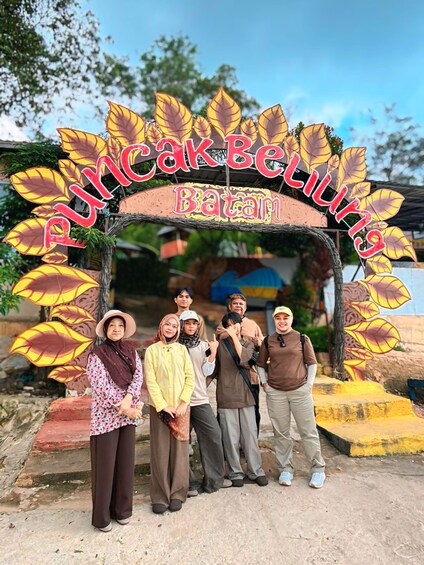 A group of people standing in front of a sign with large leaves and the text 'Puncak Belitung Batam'. 4