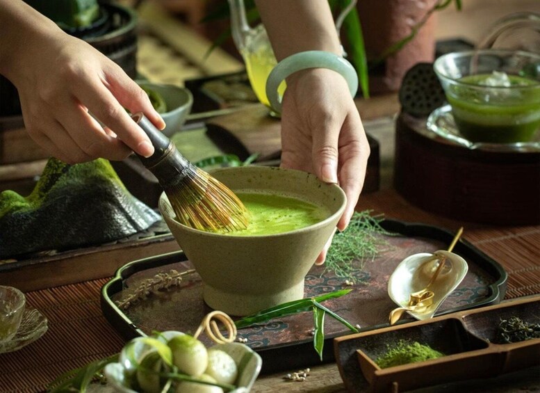 A person whisking matcha tea in a bowl. 1