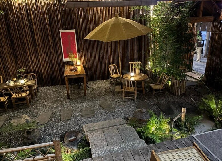 An outdoor seating area with bamboo walls, wooden furniture, and a decorative umbrella. 2