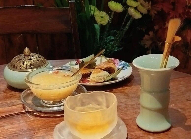 A table with a bowl of soup, a plate with pastries, a teapot, and a cup with a straw. 4