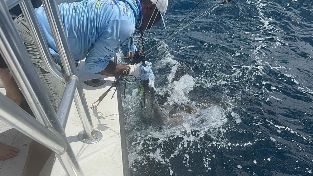 A person on a boat handling a fish. 2