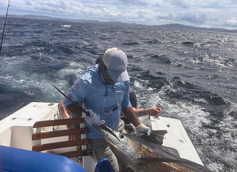 A person on a boat holding a large fish. 4