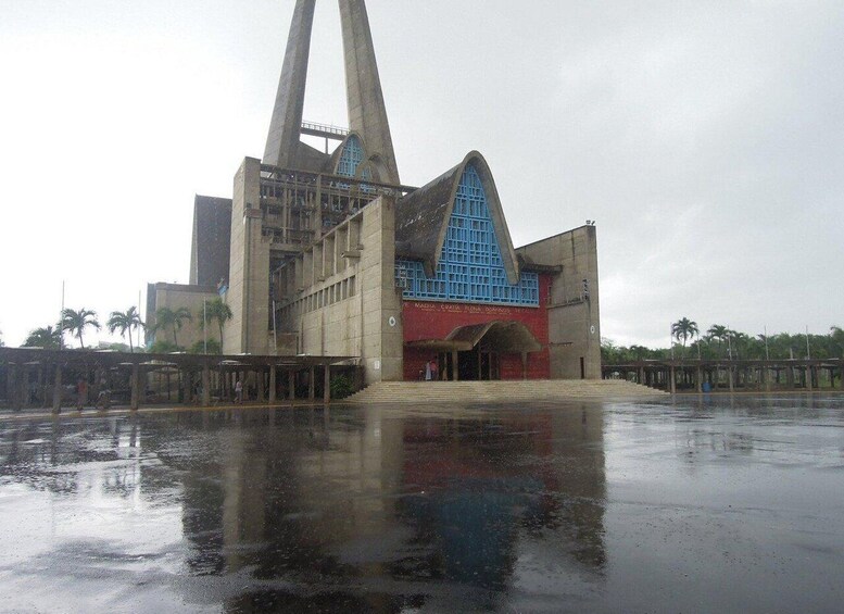 A large, modern building with a unique triangular roof and a reflective water surface in front. 2