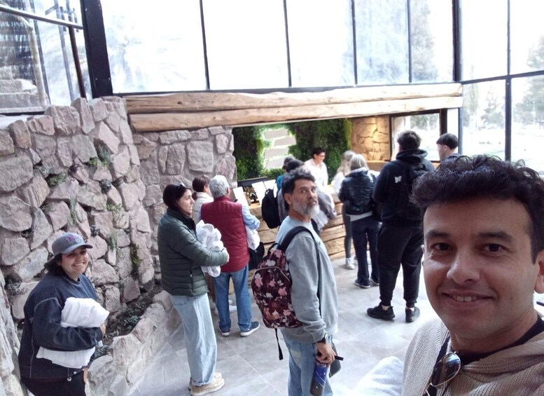 A group of people standing in an outdoor area with stone walls and a wooden structure in the background. 1