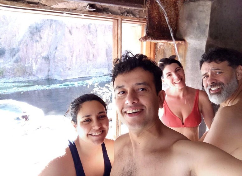 A group of people in a rustic cabin with a view of a river and rocky cliffs. 3