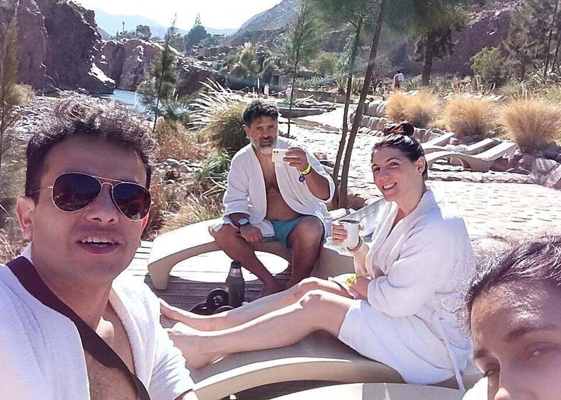 A group of people sitting on a boat on a beach with mountains in the background. 5