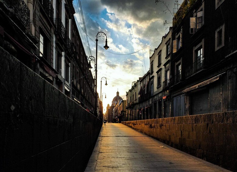 A narrow urban street flanked by historic buildings under a cloudy sky. 4