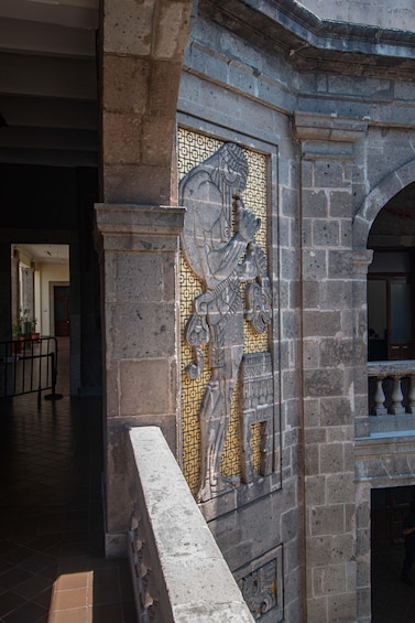 A stone wall with intricate mosaic patterns and a metal railing. 3