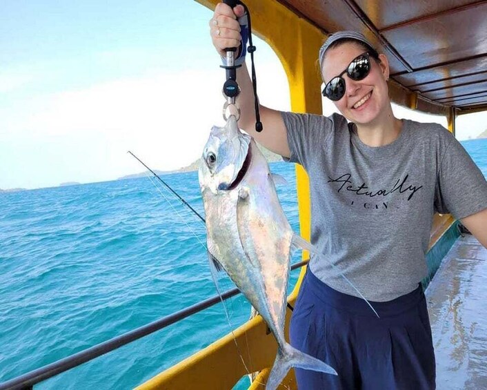 A person holding a fish on a boat with a blue ocean in the background. 1