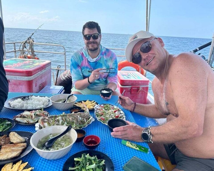 Two people dining on a boat with various dishes and a cooler. 3