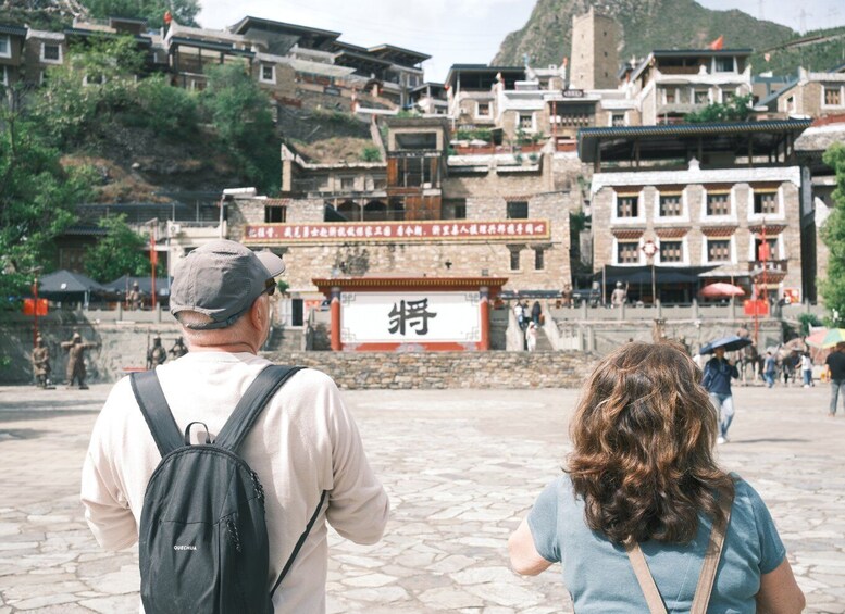 A man and a woman looking at a traditional building with a large sign in front. 1