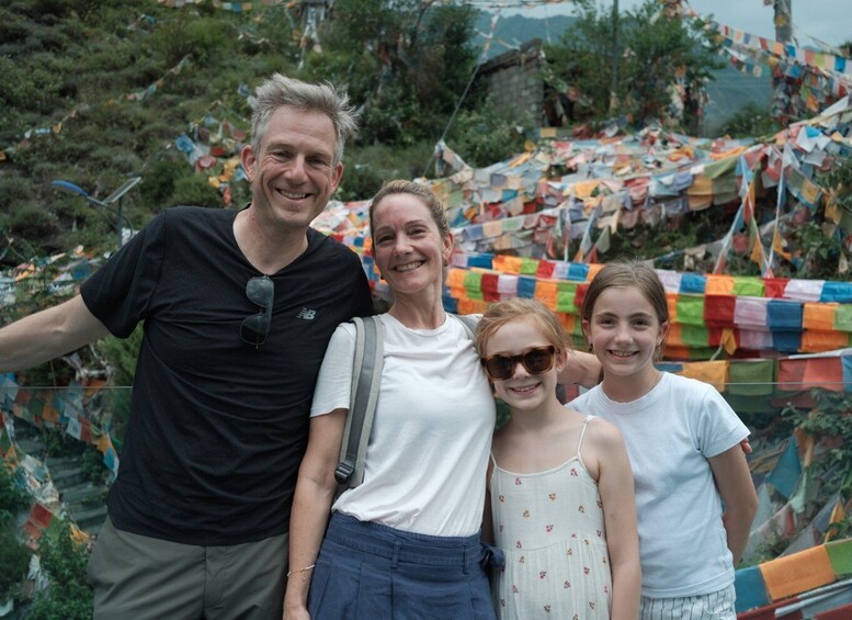 A family of four posing in front of colorful prayer flags. 5