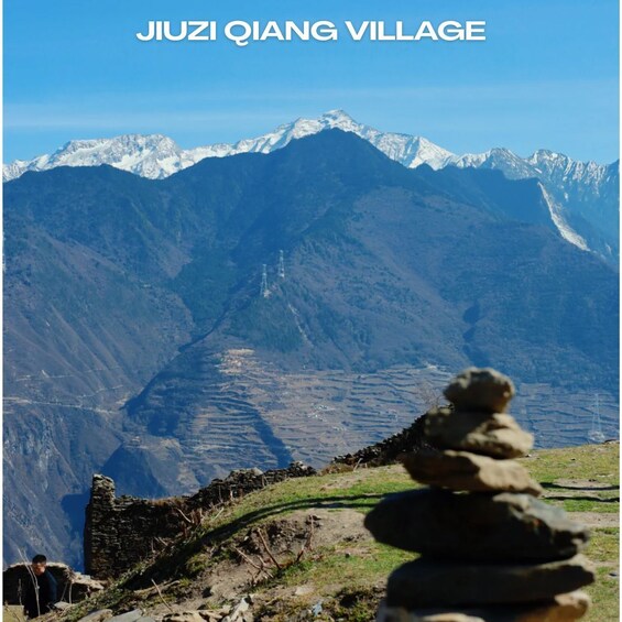 Jiuzhi Qiang Village with a mountain backdrop and a stone stack in the foreground. 3