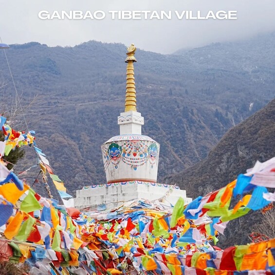 A colorful prayer flag arrangement in front of a Tibetan stupa with a golden spire, set against a mountainous backdrop. 1