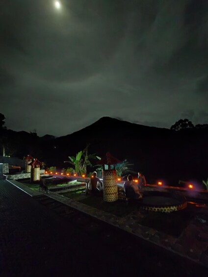 A nighttime scene with a mountain in the background, a pool area with people, and decorative lights. 3