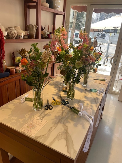 A table with vases of flowers, scissors, and a menu. 2