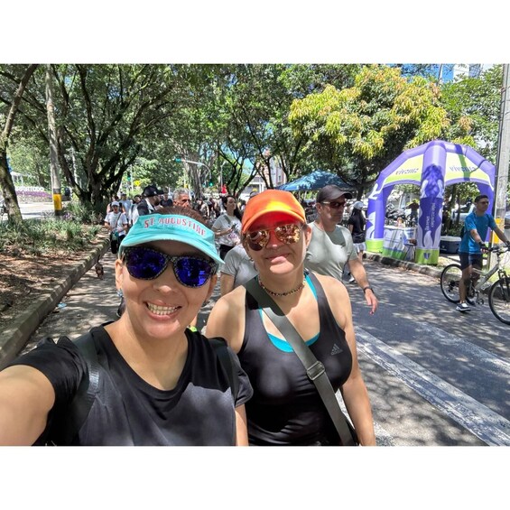 Two people taking a selfie on a tree-lined street with a purple tent in the background. 5