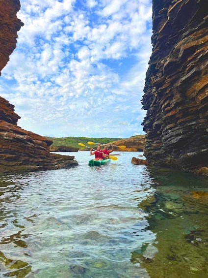 A kayaker in a narrow water channel between rocky cliffs. 1