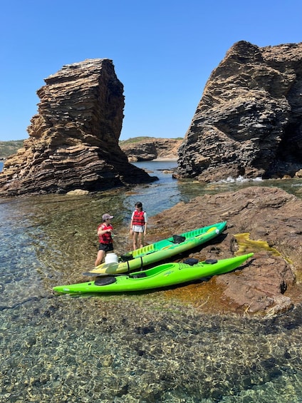 Two kayaks on a rocky shore with two people standing nearby. 5
