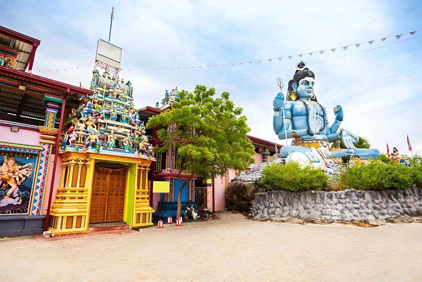 A colorful temple with a large blue statue of a deity, a mural, and a traditional entrance. 3