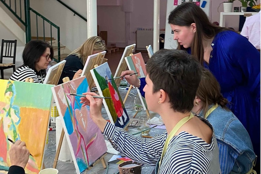 A group of people painting on easels in an indoor setting. 1