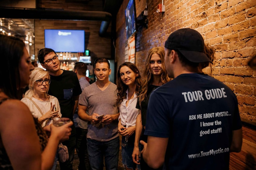 A group of people in a bar with a brick wall and a TV screen in the background. 1